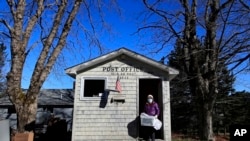 Postmistress Donna DeWitt carries mail at the tiny post office on Isle Au Haut, Maine. The post office serves the 70 or so year-round island residents, May 6, 2020.