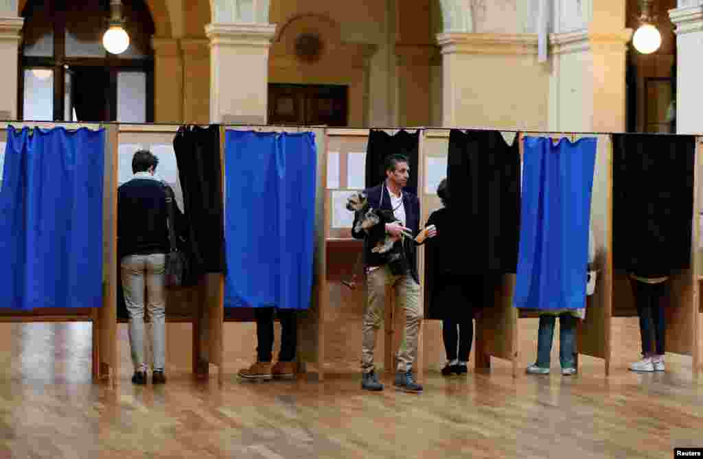 People vote in the second round of 2017 French presidential election at a polling station in Lyon, May 7, 2017.