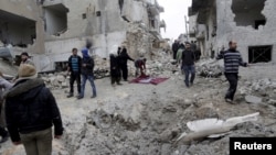 FILE - Residents inspect a crater at a site hit by what activists said were three consecutive air strikes carried out by the Russian air force, the last which hit an ambulance, in the rebel-controlled area of Maaret al-Numan town in Idlib province, Syria.