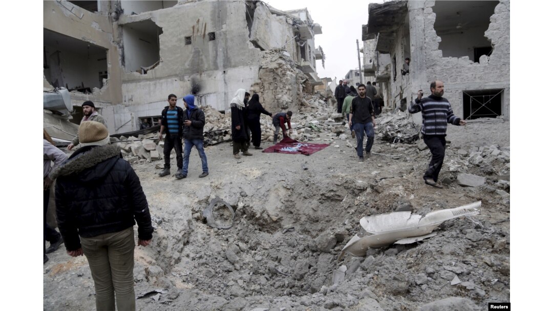 FILE - Residents inspect a crater at a site hit by what activists said were three consecutive airstrikes carried out by the Russian air force, the last which hit an ambulance, in the rebel-controlled area of Maaret al-Numan town in Idlib province, Syria, Jan. 12, 2016.