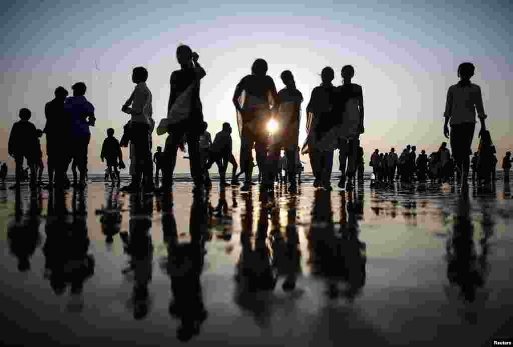 People walk on a beach along the shores of the Arabian Sea in Mumbai, India.