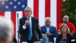 FILE - Ohio Gov. Mike DeWine, left, speaks during a vigil at the scene of a mass shooting in Dayton, Ohio, Aug. 4, 2019. 