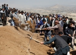 Men dig graves for the victims of yesterday's explosion during a mass funeral ceremony in Kabul, Afghanistan, May 9, 2021.