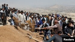 Men dig graves for the victims of yesterday's explosion during a mass funeral ceremony in Kabul, Afghanistan, May 9, 2021.