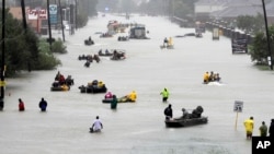 FILE - Rescue boats float on a flooded street as people are evacuated from rising floodwaters brought on by Tropical Storm Harvey on Aug. 28, 2017, in Houston, Texas.