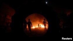 Para demonstran Palestina membakar ban dalam demonstrasi malam hari untuk menentang permukiman Israel di Beita, di wilayah Tepi Barat yang diduduki Israel, 22 Juni 2021. (Foto: Mohamad Torokman/Reuters)