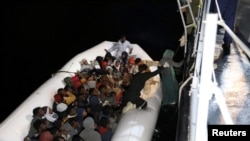 FILE - Migrants in a dinghy are rescued by Libyan members of the coast guard in the Mediterranean Sea off the coast of Libya, March 15, 2018.