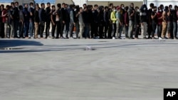 Migrants queue as they wait for their lunch in Roccella Jonica, Calabria region, southern Italy, Nov. 14, 2021.