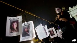 People hug next to images of murdered women following a Day of the Dead march calling for justice for victims of femicide, in Mexico City, Nov. 1, 2017. Many mothers of women who were murdered led the march wearing traditional "Catrina" face paint and carrying pictures of women who have been killed. 