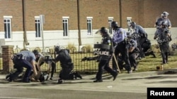 Police officers react to the shooting of an officer outside the police headquarters in Ferguson, Missouri March 12, 2015.