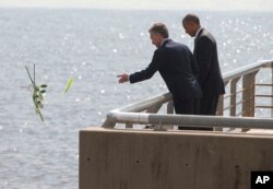 President Barack Obama watches as Argentine President Mauricio Macri tosses roses into the river during their visit to Parque de la Memoria (Remembrance Park) in Buenos Aires, Argentina, March 24, 2016.