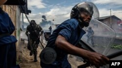 FILE - Burundi's policemen and army forces run after protesters against incumbent President Pierre Nkurunziza's bid for a third term in Bujumbura, May 13, 2015.