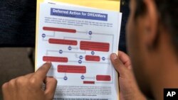 FILE - A legal immigrant reads a guide of the conditions needed to apply for the so-called 'DREAMers' Obama program, formally known as Deferred Action for Childhood Arrivals (DACA) at the Coalition for Humane Immigrant Rights, CHIRLA offices in Los Angeles, Aug. 15, 2012.