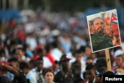 An image of Cuba's late President Fidel Castro is raised as people wait for the arrival of the caravan carrying Castro's ashes in Santiago de Cuba, Cuba, Dec. 3, 2016.