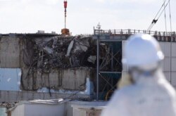 រូបឯកសារ៖ អ្នកយកសារព័ត៌មានម្នាក់ដែលស្ថិតក្នុងសម្លៀកបំពាក់ការពារសារធាតុពុល ពិនិត្យមើលម៉ាស៊ីន​រ៉េអាក់ទ័រទី ៣ នៅទីស្នាក់ការរបស់ក្រុមហ៊ុនផលិតថាមពលនុយក្លេអ៊ែរ Tokyo Electric Power Co's (TEPCO) នៅក្រុង Okuma តំបន់ Fukushima ប្រទេសជប៉ុន កាលពីថ្ងៃទី ១០ ខែកុម្ភៈ ឆ្នាំ ២០១៦។