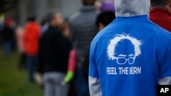 A man in a Bernie Sanders shirt waits in a line to vote at a Democratic caucus site Tuesday, March 22, 2016.