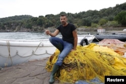 FILE - Greek fisherman Stratis Valiamos takes a break at the port of a fishing village in the Greek island of Lesbos, Oct. 21, 2015.