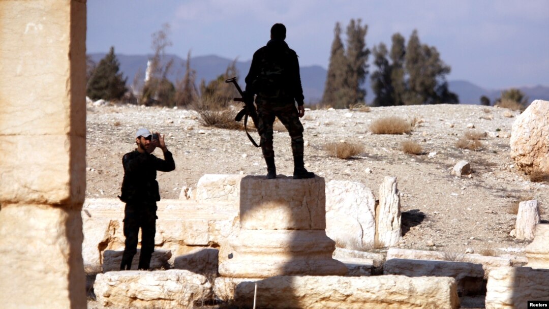 A Syrian army soldier takes a picture of a fellow soldier standing on ruins in the historic city of Palmyra, Syria, March 4, 2017.