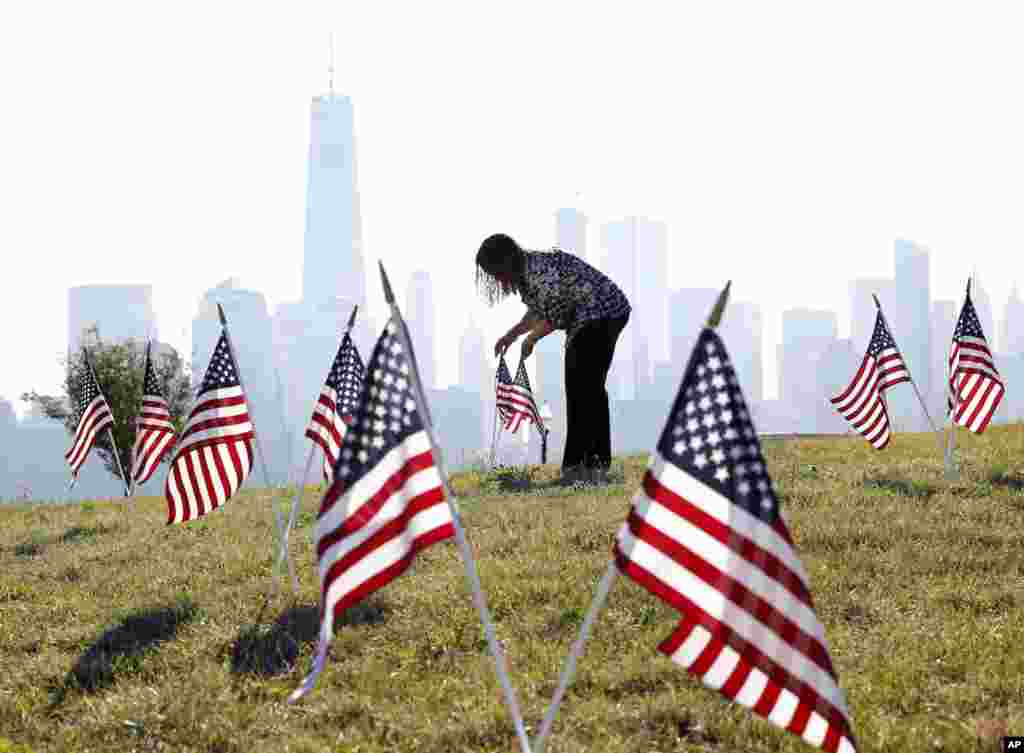 Yalenny Vargas mengatur posisi bendera AS pada perayaan HUT kemerdekaan Amerika di taman Liberty di Jersey City, negara bagian New Jersey.