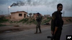 A U.S.-backed Syrian Democratic Forces fighter talks on a radio at a checkpoint near Omar oil field base, eastern Syria, Feb. 24, 2019.