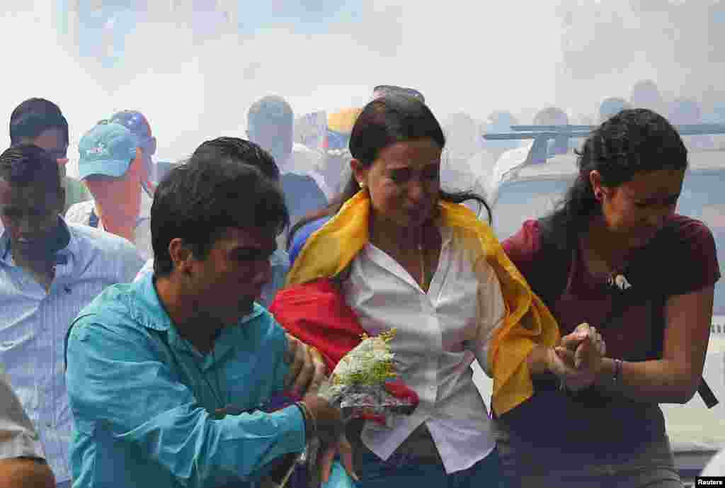 Venezuela's opposition leader Maria Corina Machado runs away from tear gas after she tried to take her seat at the national assembly in Caracas, Apr. 1, 2014. Congress last week stripped opposition deputy Maria Corina Machado of her post in parliament on charges of violation of the constitution by speaking at the Organization of American States with the backing of the Panamanian government.