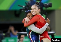 Simone Biles (L) and Aly Raisman celebrate winning gold and silver respectively at the women's individual all-around final in Rio de Janeiro, Brazil, Aug. 11, 2016.