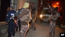 Masked Turkish police officers secure the perimeter outside a house during an operation to arrest people for alleged links to Islamic State group in Adana, Turkey, Nov. 10, 2017. 