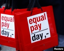 FILE - People carry bags reading 'equal pay day' in Bern, Switzerland, March 7, 2015.