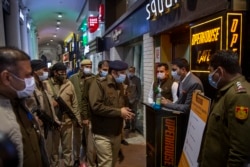 A Delhi Police officer speaks to a restaurant manager while patrolling Connaught Place, Delhi's famous and oldest shopping area, amid restrictions imposed due to rising numbers of COVID-19 cases, on New Year's Eve in New Delhi, India, Dec. 31, 2021.