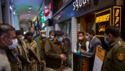 A Delhi Police officer speaks to a restaurant manager while patrolling Connaught Place, Delhi's famous and oldest shopping area, amid restrictions imposed due to rising numbers of COVID-19 cases, on New Year's Eve in New Delhi, India, Dec. 31, 2021.