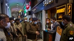 Un officier de police de Delhi parle à un directeur de restaurant alors qu'il patrouillait sur Connaught Place, le quartier commerçant le plus célèbre et le plus ancien de Delhi, au milieu des restrictions imposées en raison du nombre croissant de cas de COVID-19, le soir du Nouvel An à New Delhi, en Inde, le 31 décembre 2021.