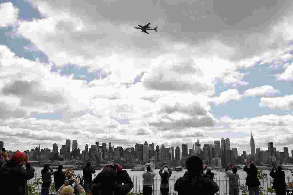 Space shuttle Enterprise, riding atop NASA's 747 Shuttle Carrier Aircraft, flies past the skyline of Manhattan as seen from Weehawken, New Jersey during a flyover in New York, April 27, 2012. 