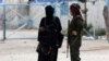 یک نگهبان کرد عضو نیروهای دموکراتیک سوریه در کنار زن یک شبه نظامی داعشی که هر دو در سوریه بازداشت شده اند - آرشیو