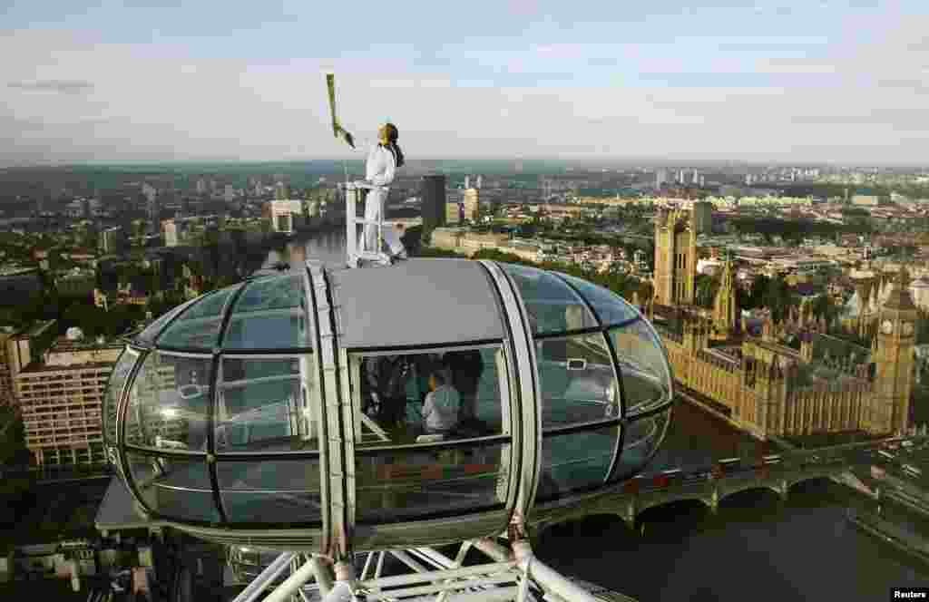 Pembawa obor Amelia Hempleman-Adams, 17, berdiri di atas salah satu kapsul London Eye sebagai bagian dari proses estafet obor Olimpiade (22/7). 