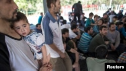 在泰国-马来西亚边界被拘留的一个疑似来自新疆的维吾尔人抱着孩子在临时收容所里（2014年3月14日）