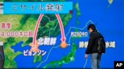 A man stands in front of a huge screen showing TV news program reporting North Korea's missile launch, in Tokyo, Nov. 29, 2017. 