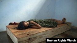 Perempuan berusia 24 tahun berbaring di bale-bale dengan pergelangan tangan dan kaki yang dirantai di pusat penyembuhan Bina Lestari di Brebes, Jawa Tengah. (Human Rights Watch/Andrea Star Reese)