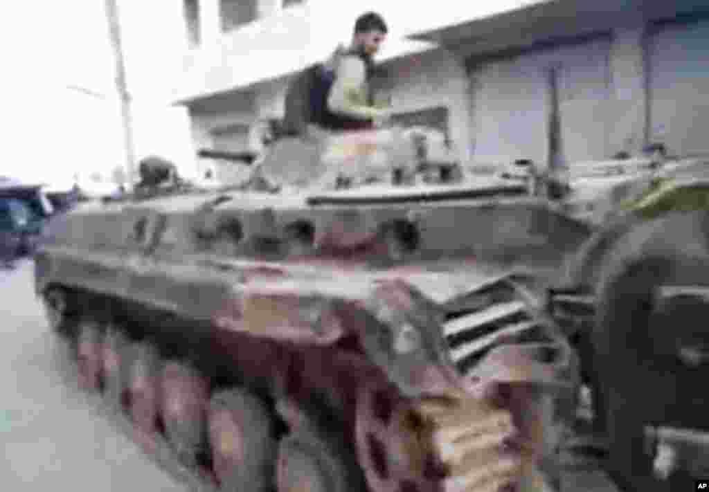 This image from amateur video and released by Shaam News Network purports to show a Syrian rebel atop of a Syrian military tank in Khan Sheikhoun, Syria, March 13, 2012. (AP/Shaam) 