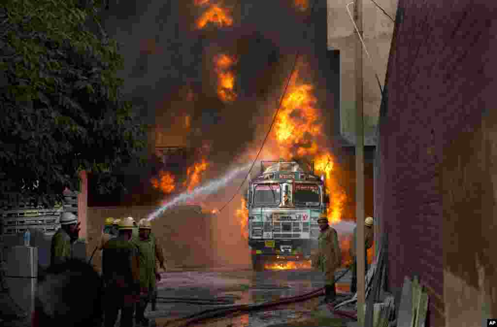 Firefighters work to douse flames on a truck in New Delhi, India. The fire that started in a truck spread to a nearby warehouse. No casualties have been reported.