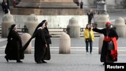 FILE: Cardinal Francis Arinze of Nigeria waves at nuns as he arrives for a meeting at the Synod Hall at the Vatican. Taken 3.13.2013