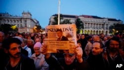 FILE - A man holds up the last printed edition of Nepszabadsag during a demonstration organized to express solidarity with the Hungarian political daily Nepszabadsag in Budapest, Hungary, Oct. 8, 2016. 