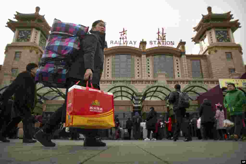 2018年2月9日，一名妇女在北京火车站外携带行李箱。下周农历新年假期前，数百万中国人乘坐火车，飞机和汽车旅行，春运高潮预计本周末开始。