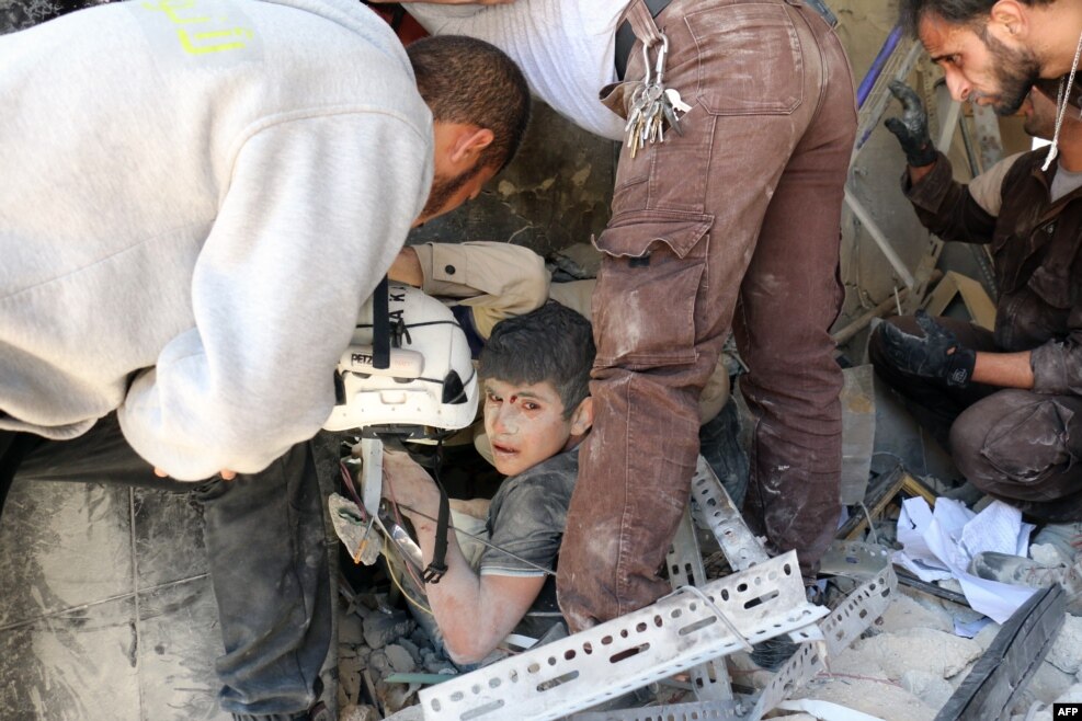 Syrian civil defense volunteers help a boy out of the rubble following a reported attack by government forces in the Tariq al-Bab neighborhood in the northern city of Aleppo.