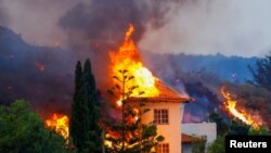 Sebuah rumah terbakar akibat lahar dari letusan gunung berapi di taman nasional Cumbre Vieja, Los Llanos de Aridane, Pulau Canary La Palma, 20 September 2021. (REUTERS/Borja Suarez)
