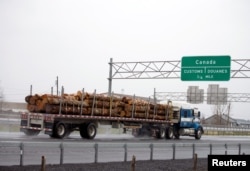 A truck carrying logs heads toward the Canada border in Champlain, N.Y., April 25, 2017.