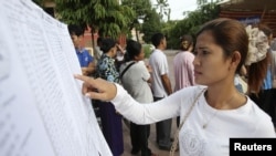 A woman finds her name on a list during a local commune election in Phnom Penh, June 3, 2012.