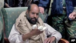 Video image made available Nov. 22, 2011 shows Moammar Gadhafi's son Seif al-Islam examining his injured hand shortly after his capture on November 19, 2011, at a safe house in the town of Zintan