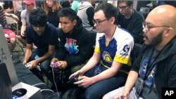 In this Aug. 25, 2017, photo, Connor Nguyen, at right, and Griffin Williams, second from right, compete in 'Super Smash Bros. Melee' at the Shine eSports event at the Seaport World Trade Center in Boston, Massachusetts. (AP Photo/Collin Bi