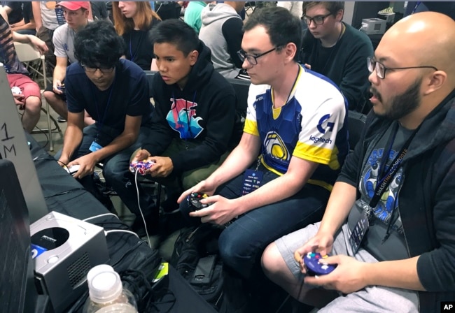 In this Aug. 25, 2017, photo, Connor Nguyen, at right, and Griffin Williams, second from right, compete in a "Super Smash Bros. Melee" tournament at the Shine eSports festival at the Seaport World Trade Center in Boston, Massachusetts. (AP Photo/Collin Binkley)