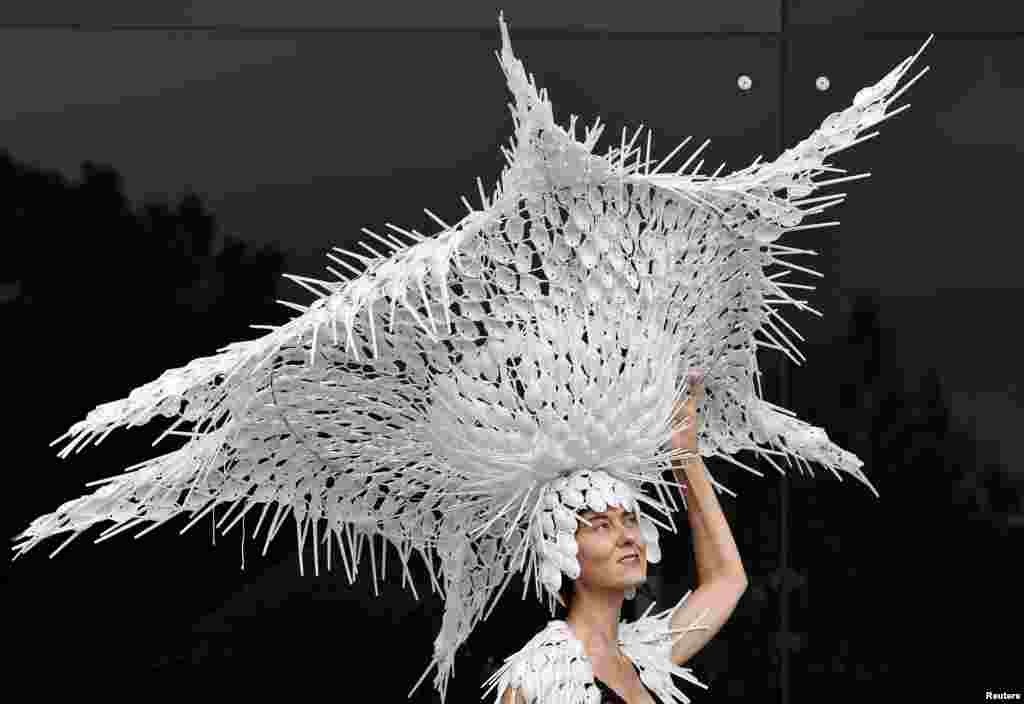 Seorang penonton pacuan kuda Larisa Katz berpose dengan topi yang ia desain dari sendok plastik daur ulang ketika menghadiri hari kedua pacuan kuda Royal Ascot di Inggris.